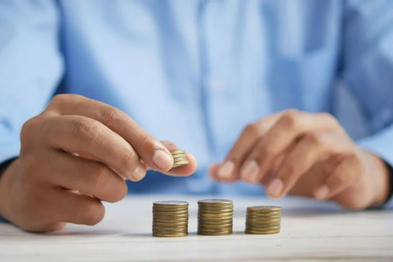 Person arranging coins into stacks on a table