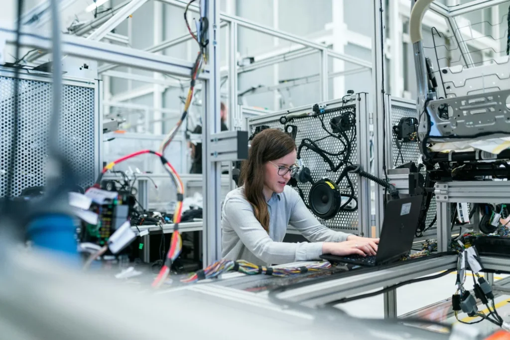 Engineer using a laptop beside industrial equipment