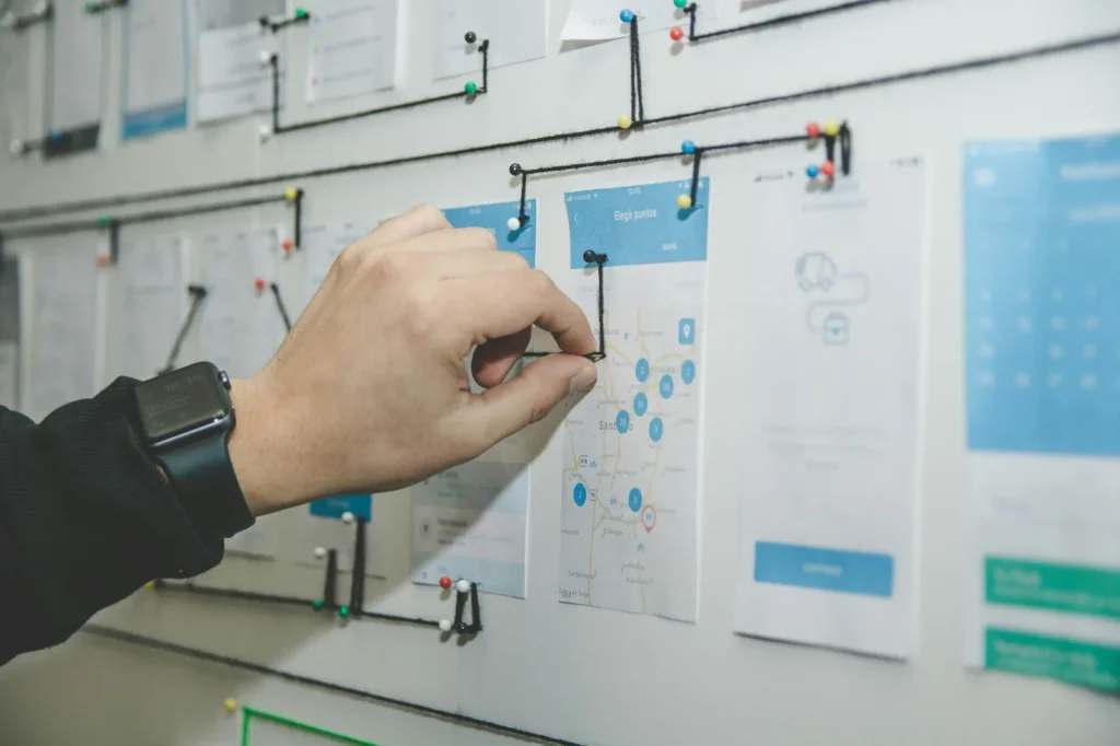 A hand arranging interface sketches on a planning board.