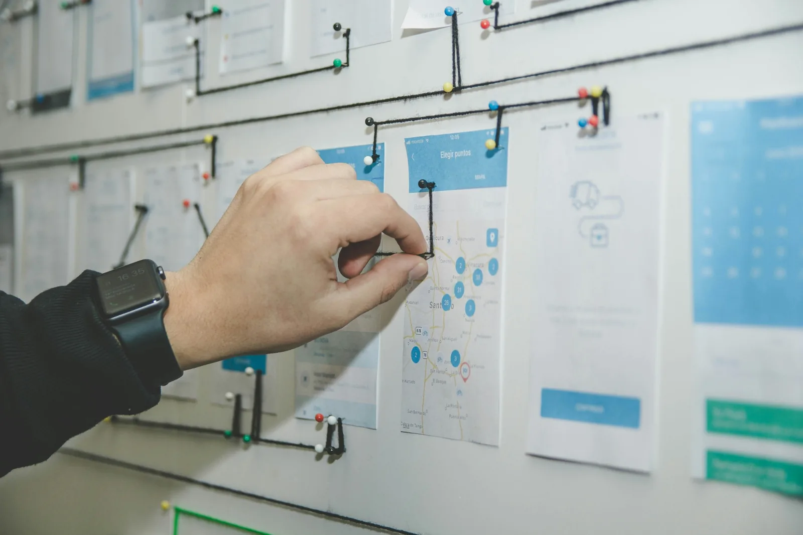 A hand arranging interface sketches on a planning board.
