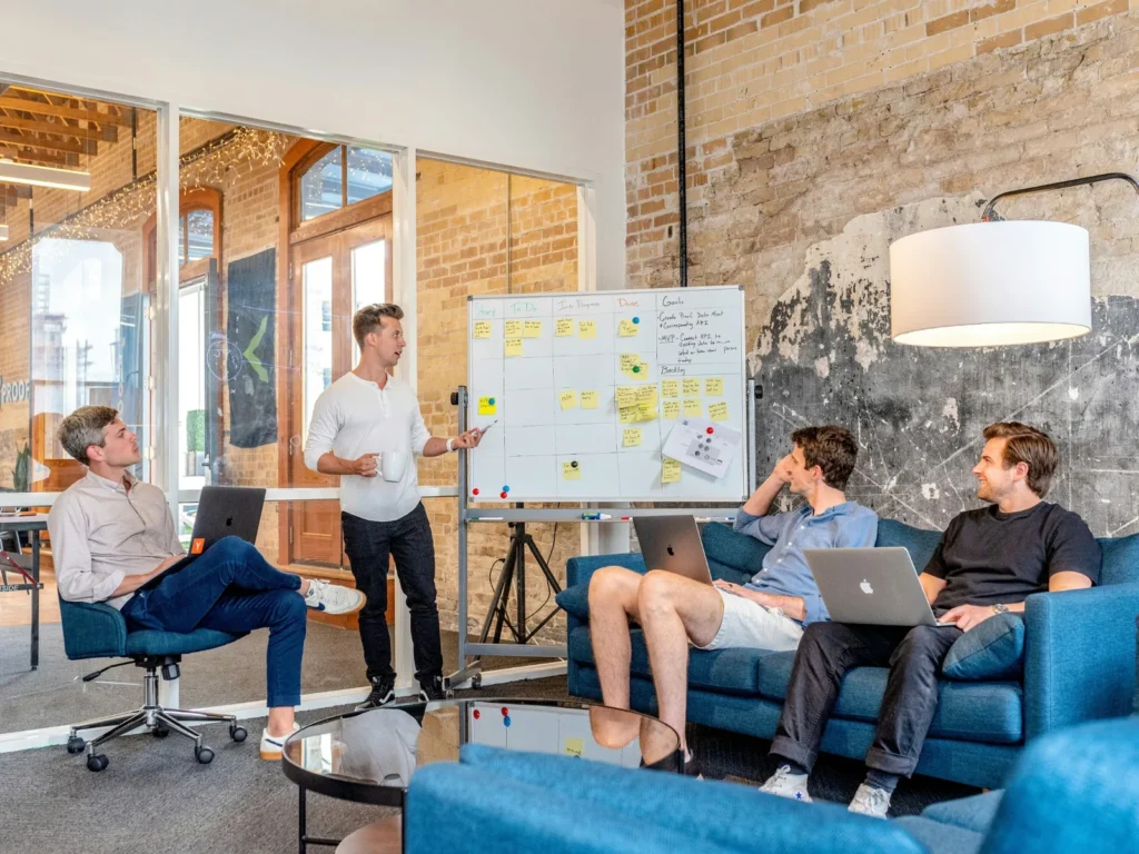 Colleagues discussing a project around a whiteboard in an office.