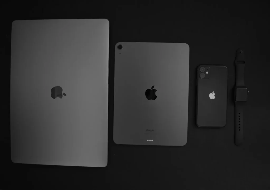 Laptop, tablet and phone arranged on a dark desk