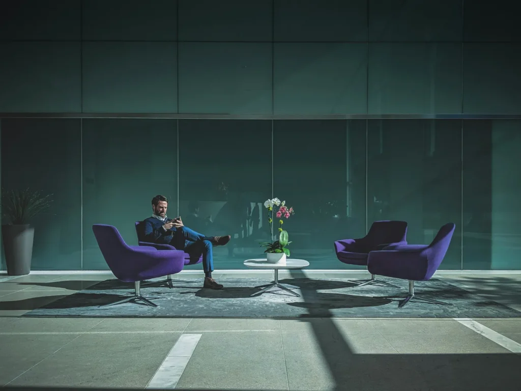 Person seated in a modern lounge with purple chairs