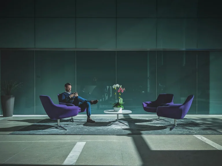 Person seated in a modern lounge with purple chairs