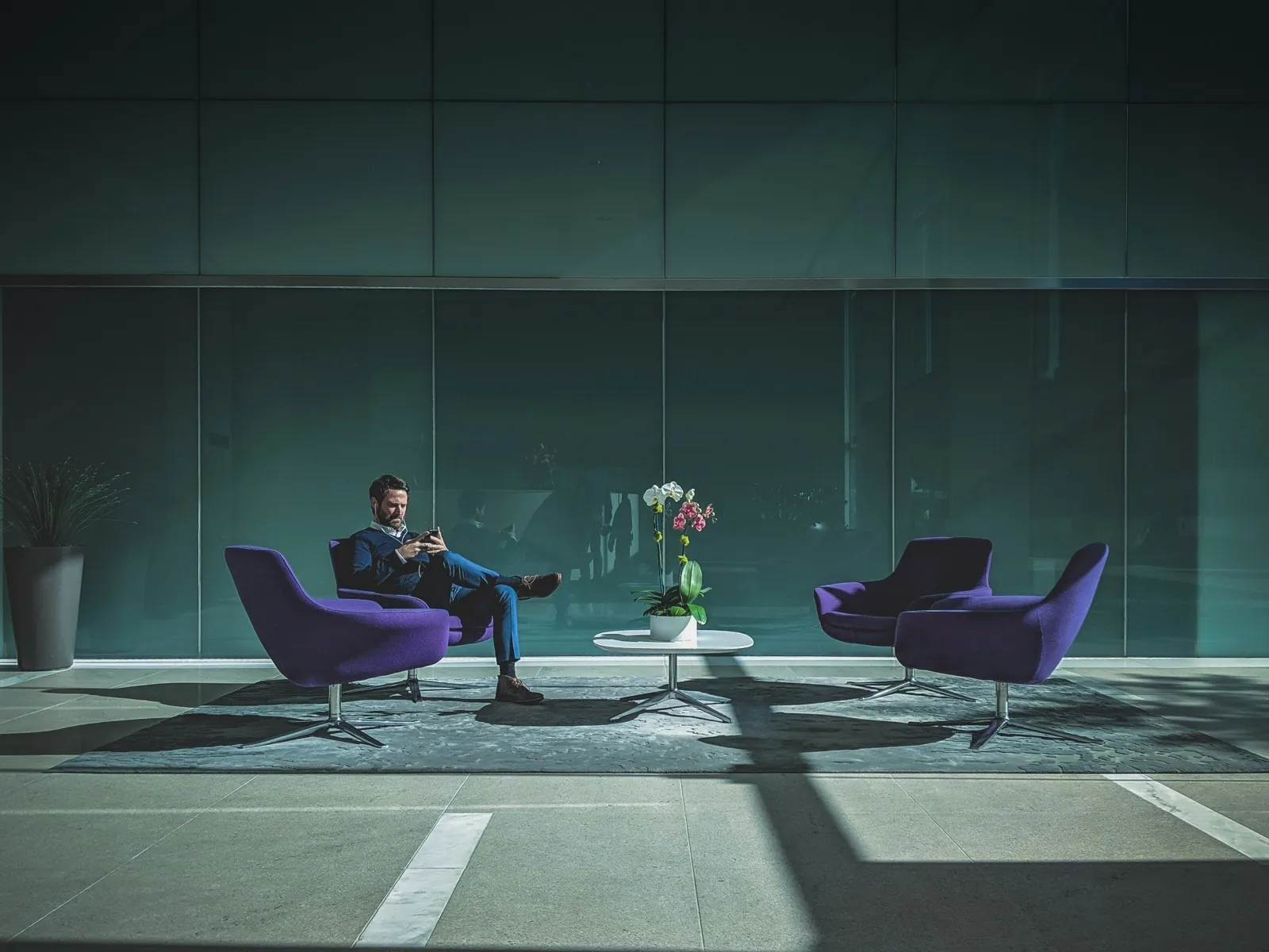 Person seated in a modern lounge with purple chairs