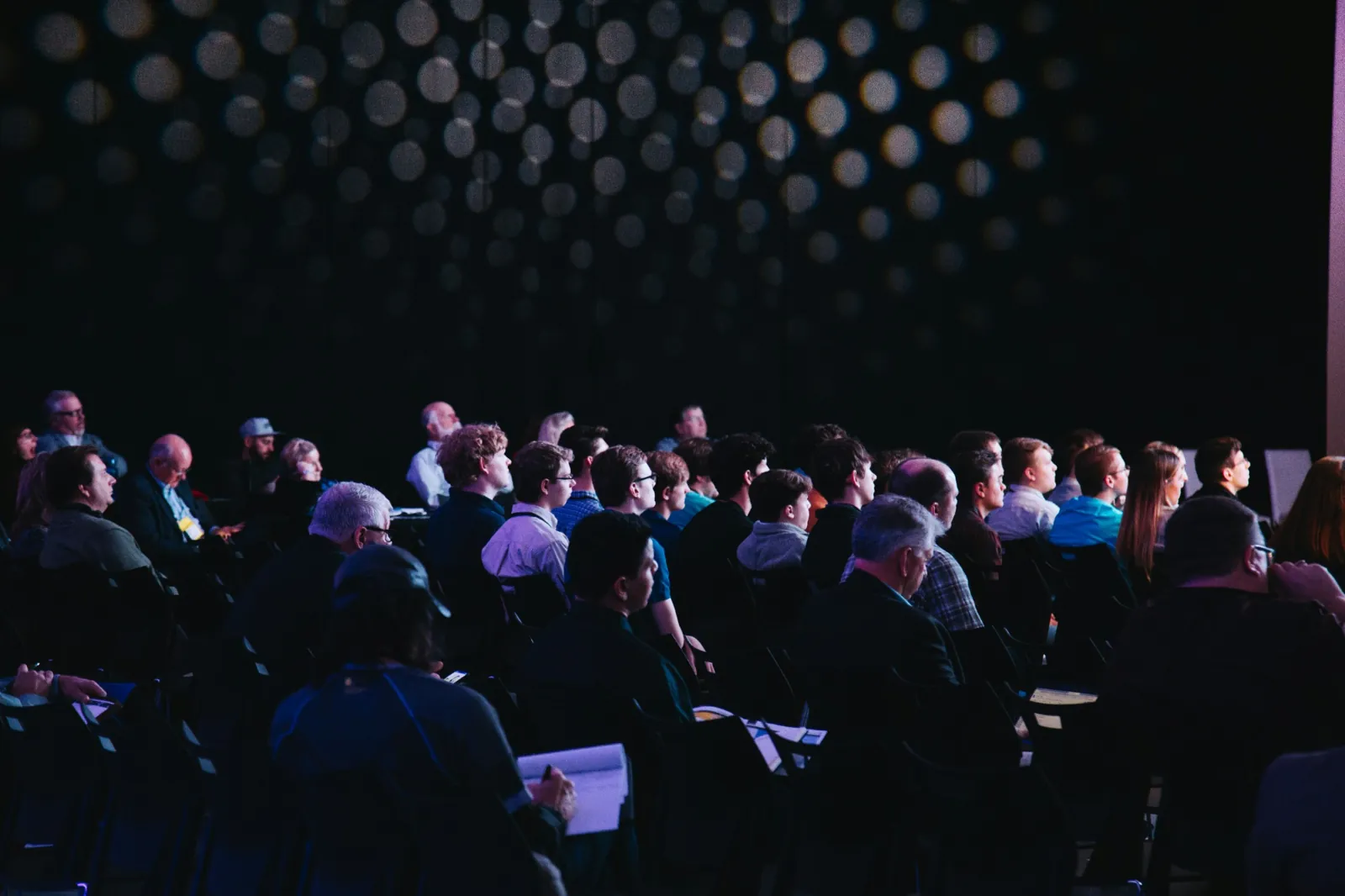 Seated audience facing a presentation in a darkened room