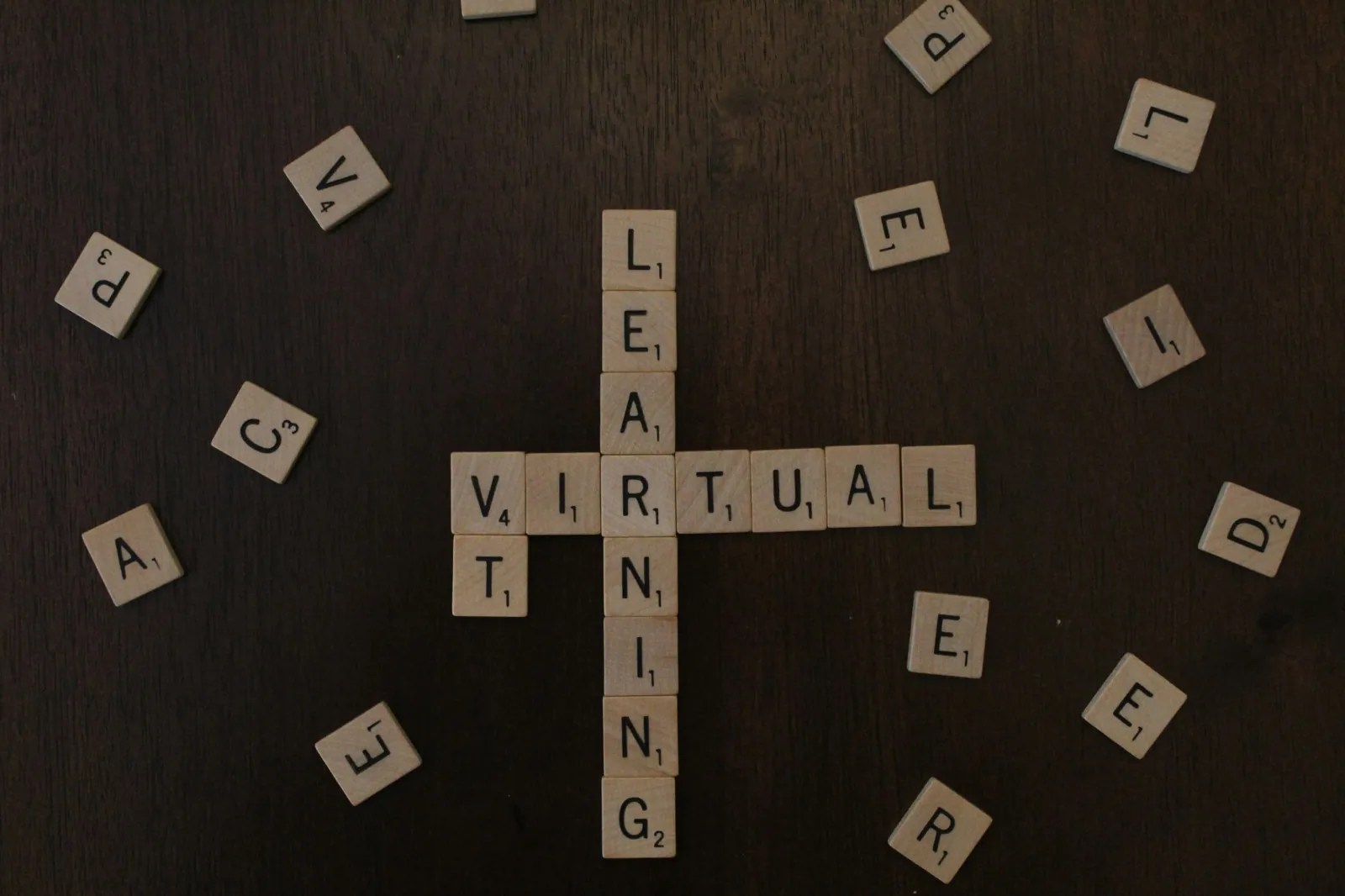 Wooden letter tiles spelling Virtual and Learning on a dark surface