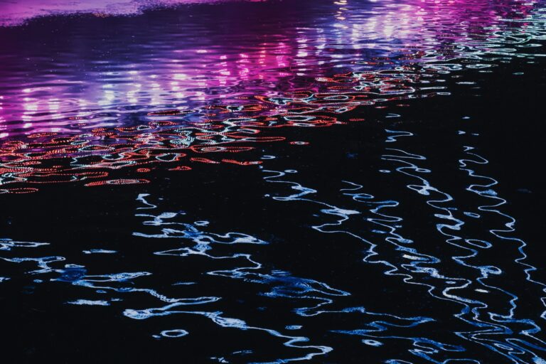 Purple and blue lights reflected on rippling water