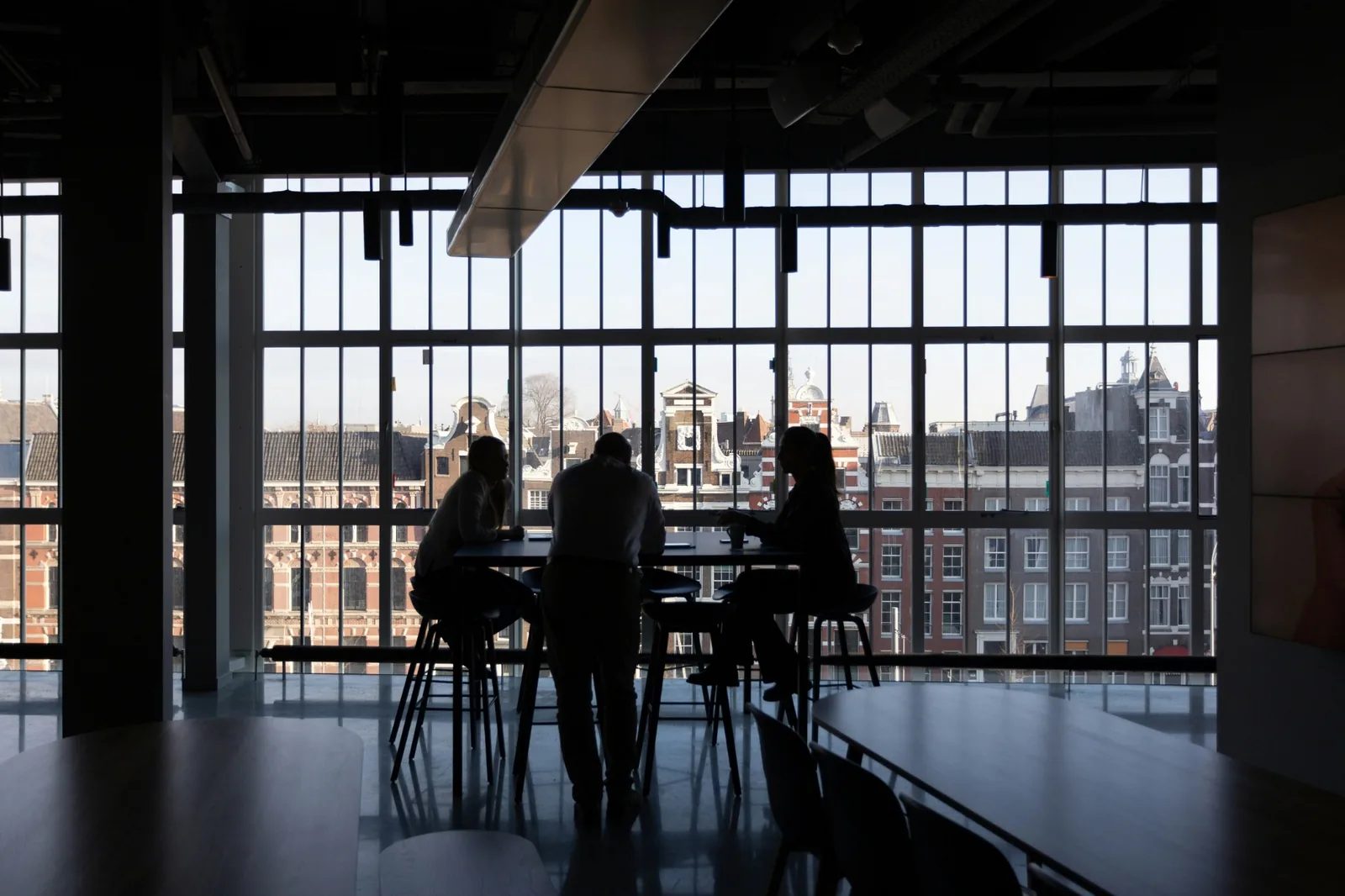 Silhouettes of colleagues meeting beside floor-to-ceiling windows