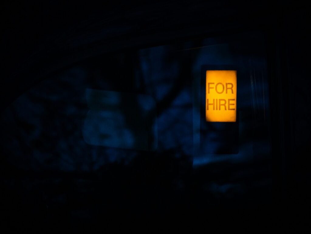 Illuminated For Hire sign against a dark background
