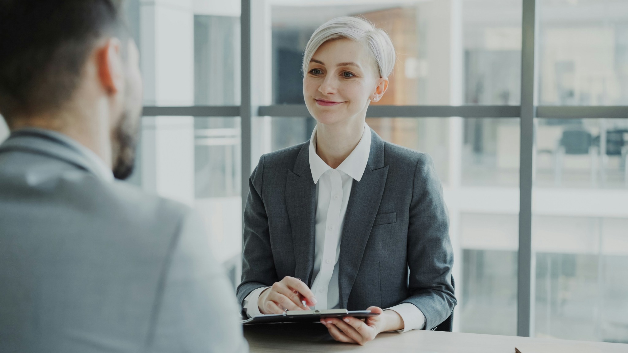 Two people talking across a desk during an office meeting
